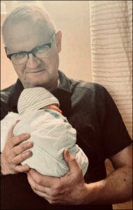 Robert Kyler holds new grandchild for The Big 65 Colorado.