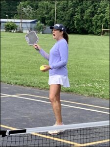 USPTA Certified Teaching Pro Pam Lippy holding a pickleball racquet and ball.