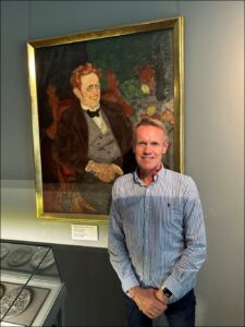 Karl Kyler standing in front of painting of his great grandfather, Karl Masner.