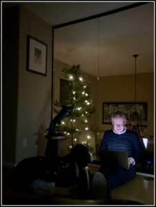 Karl Bruns-Kyler working on Medicare in front of a Christmas tree decorated with white lights. 