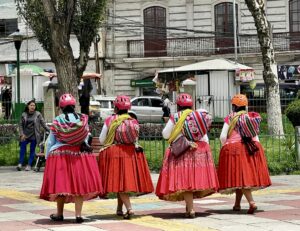 Four ladies in colorful outfits walking down the street together.