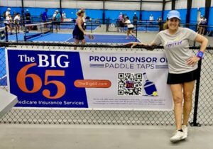 Pam Lippy poses in front of The Big 65 banner at Paddle Taps.