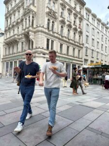 Chris and Nicholas walking down the street with food in hand.
