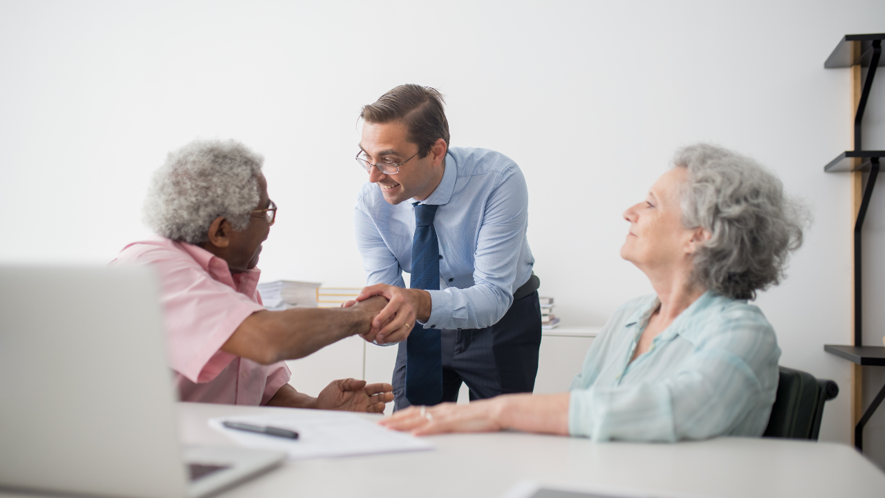 insurance broker shaking hands with an elderly woman