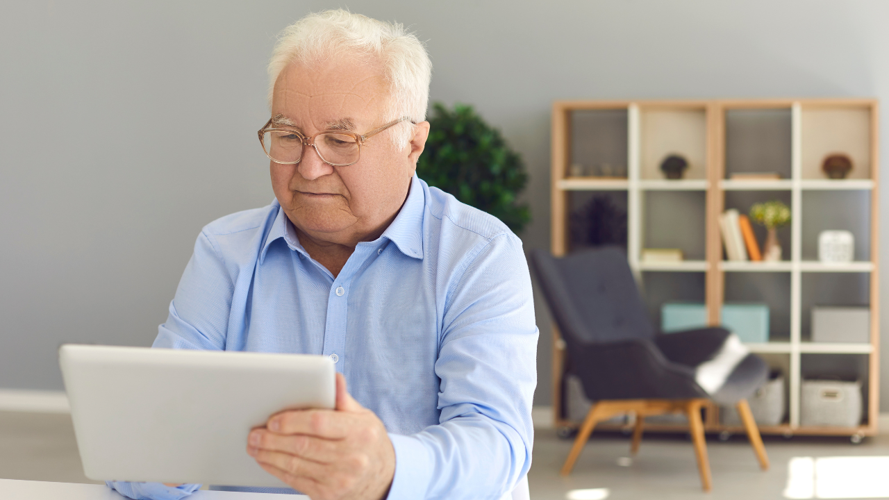 An old man using a white tablet