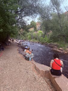  Groups of people sitting on the edge of the North Saint Vrain Creek in Colorado.