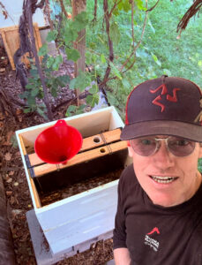 Karl looking up at the camera next to his bee hive.