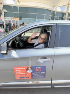 Quantz sitting in the driver's seat of a car waving at the camera.