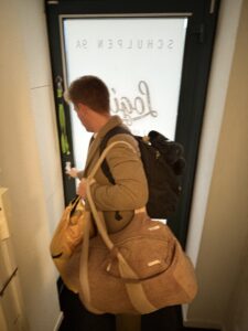 Nicholas carrying bags and opening a door.