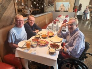 Karl sitting at a restaurant table with his two brothers.