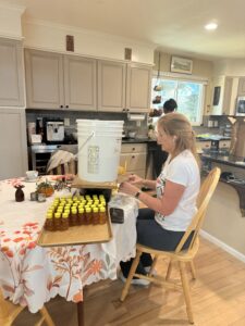 Quantz sitting at a table filling containers with honey.