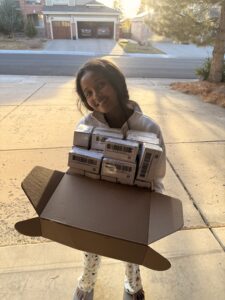 Miti holding a box of honey containers.