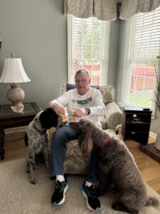 Another satisfied client of The Big 65 holding honey and surrounded by his two dogs.