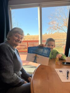 Catherine and her grandson who is showing his picture.