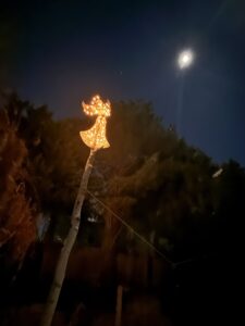 Angel sitting on the top of a pole with the moon in the background.