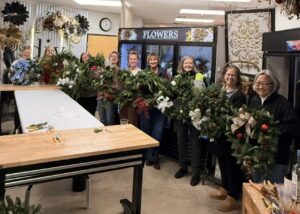 A group of ladies each holding a Christmas wreath.