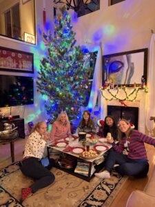 A group of woman sitting in front of a Christmas tree.