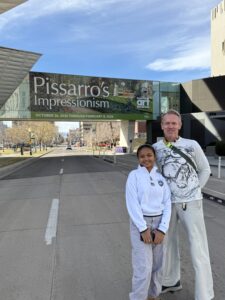 Karl and Mitia standing in front of sign for the Pissaro exhibit.