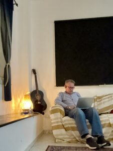 Karl sitting on a sofa and working on his computer helping a Medicare client.