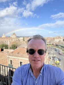 A selfie of Karl with a rainbow in the background.