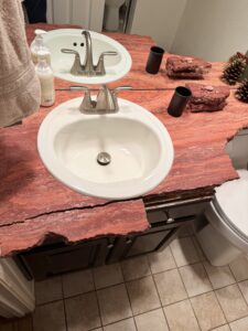 A bathroom sink surrounded by a red rock.