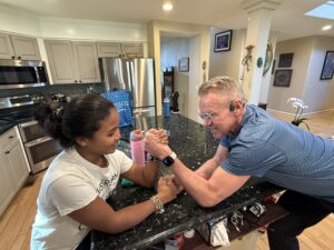 Karl arm wrestling Miti in the kitchen.