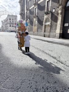 Young boys carrying something through the street.