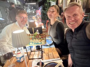 Three attractive people sitting at a table and smiling at the camera.
