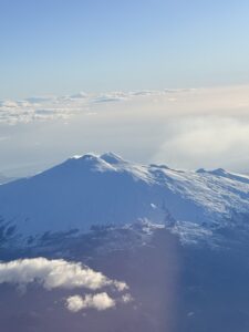 A volcano in the distance as seen from an airplane in the sky.