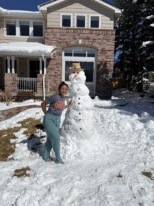 Miti standing next to a snowman.