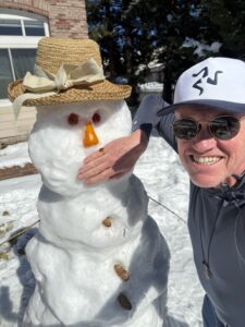 Karl with his right hand over a snowman's mouth.
