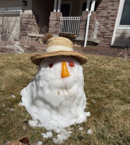 A melting snowman with a straw hat, two red eyes, and an orange nose.