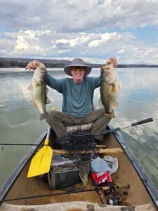 Karl's brother Haas sitting in a boat and holding two big fish, one in each hand.