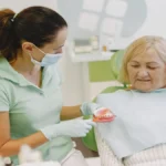 Senior woman smiling while dental professional explains Medicare dental coverage options