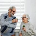 Senior couple smiling in a bright kitchen representing healthy aging and Medicare hearing aid coverage options
