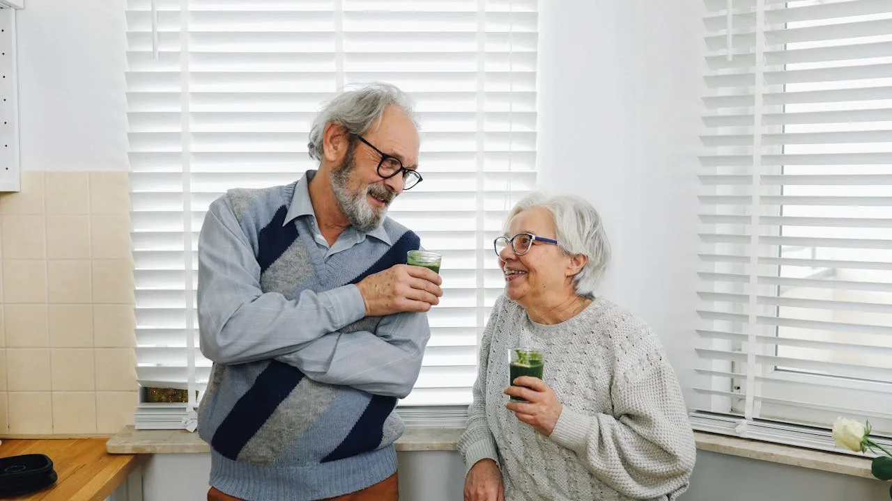 Senior couple smiling in a bright kitchen representing healthy aging and Medicare hearing aid coverage options