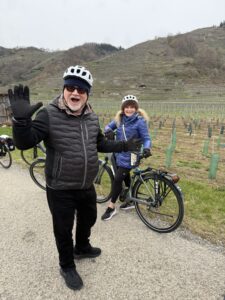 A man and a woman near their bikes near a vineyard.