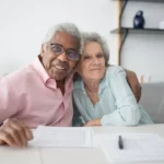 Senior couple reviewing Medicare insurance documents at kitchen table, considering switching from Medicare Advantage to Medigap