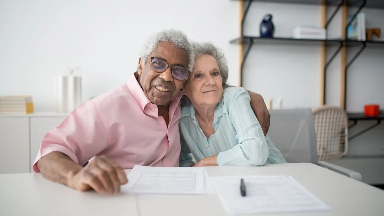 Senior couple reviewing Medicare insurance documents at kitchen table, considering switching from Medicare Advantage to Medigap