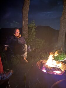 A man sitting in front of a campfire.