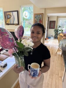 Miti holding flowers and a cup of coffee for Quantz on Mother's Day.