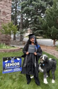 Miti holding her high school diploma as Plato, the big black and white dog, looks up at her.