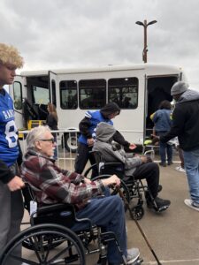 People helping each other next to a white bus.