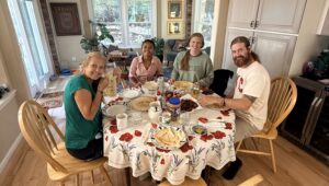 A group of people sitting at a kitchen table looking at the camera.