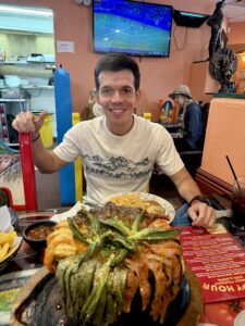 Santiago sitting at a restaurant table in front of a big plate of food.