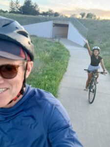 Karl and Miti on bikes waving at the camera.