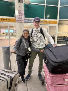 Karl and Mitia holding onto suitcases at the Denver airport.