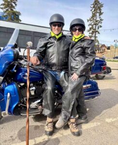 Two people in black next to a motorcycle.