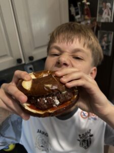 Justin eating a huge hamburger.