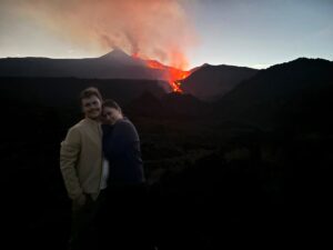 A cute couple standing in front of a volcano.